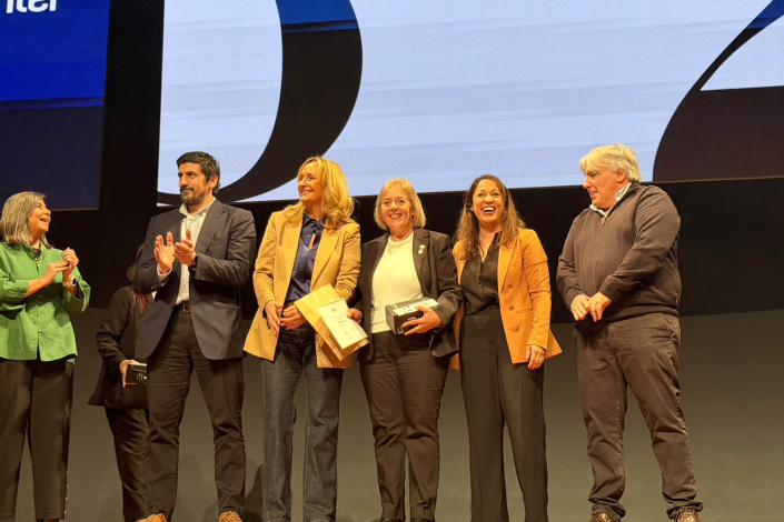 Autoridades de Antel, sobre un escenario; una fuincionaria con un diploma